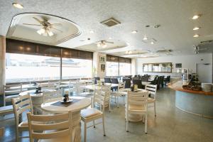 a restaurant with white chairs and tables and a bar at Kanku Sun Plus Yutaka in Izumi-Sano