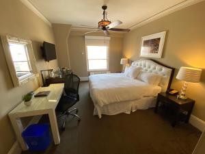 a bedroom with a white bed and a desk and a chair at Kensington Park Hotel in San Francisco