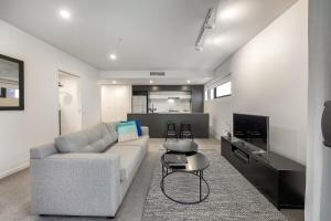 a living room with a couch and a tv at Opera Apartments South Brisbane in Brisbane