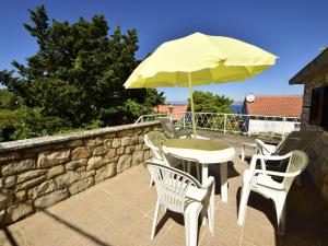 a table and chairs with an umbrella on a patio at Holiday Home Villa Palma by Interhome in Postira