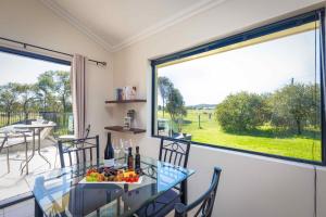 ein Esszimmer mit einem Tisch und einem großen Fenster in der Unterkunft Mandalay Villas - Villa 1 in Paxton