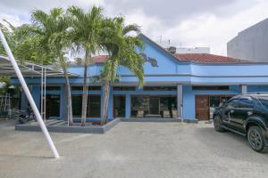 a blue building with palm trees in front of it at SUPER OYO 2320 Hotel Charvita in Kupang