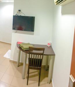 a table with a chair and a television on a wall at Melawati Ria Hotel in Kuala Selangor