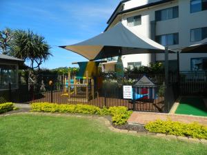 a fence with an umbrella and a playground at Princess Palm on the Beach in Gold Coast
