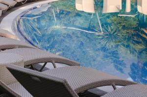 a group of chairs sitting in front of a swimming pool at Villa Nicolli Romantic Spa Resort - Adults Only in Riva del Garda
