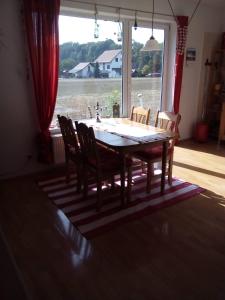 einen Esstisch mit Stühlen und ein großes Fenster in der Unterkunft Ferienwohnung Fabricio in Dolní Lánov
