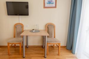 a dining room table with two chairs and a tv at Vikondos Poilsio Namai in Palanga