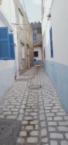 an empty alley with a blue door and a building at Dar Warda in Bizerte