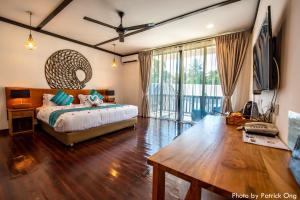 a bedroom with a bed and a table and a tv at Borneo Divers Mabul Resort in Pulau Mabul 