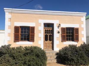 ein Haus mit braunen Fensterläden und einer Tür in der Unterkunft The Dusty Vine in Philippolis