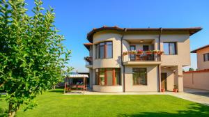 une maison avec une pelouse verte devant elle dans l'établissement KATERINA guest house, à Kocherinovo