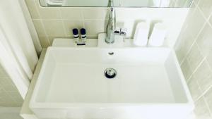 La salle de bains est pourvue d'un lavabo blanc et d'un robinet. dans l'établissement Hôtel Noir, à Paris