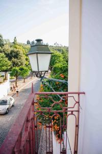 a balcony with a lamp and flowers on a street at Casa João Chagas Guesthouse, Constância in Constância