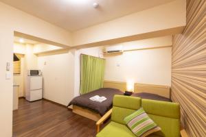 宜野灣的住宿－露台度假8號公寓式酒店，小房间设有一张床和一把绿色椅子