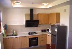 eine Küche mit Holzschränken und einem schwarzen Kühlschrank in der Unterkunft Sultan Palace Beach Resort - AMANI Apartment CB2-202 in Kikambala