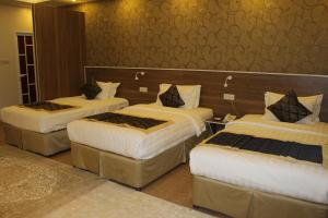 pokój hotelowy z 3 łóżkami z białą pościelą w obiekcie Al Diyar Hotel w mieście Nizwa
