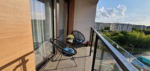 a balcony with two chairs and a view of a city at APARTAMENT DĄBSKA 24 TAURON ARENA in Kraków