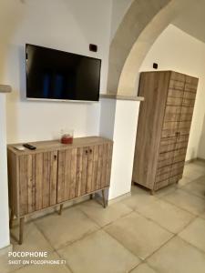 - un salon avec une télévision et des placards en bois dans l'établissement Appartamento Suite Santa Teresa, à Tarente