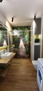 a bathroom with a wall mural of a forest at APARTAMENT DĄBSKA 24 TAURON ARENA in Krakow