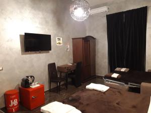 ein Wohnzimmer mit einem TV und einem Schreibtisch mit einem Stuhl in der Unterkunft B&B Roma Royal Residence in Rom