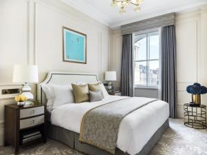 a bedroom with a large white bed and a window at The Langham London in London