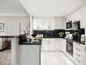a kitchen with white cabinets and black counter tops at The Langham London in London