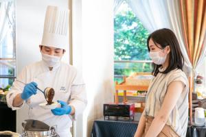 a man and a woman in chefs gear preparing food at Hotel Hewitt Koshien in Nishinomiya