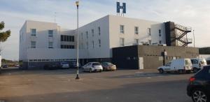 Un gran edificio con coches aparcados en un estacionamiento. en Norte Hotel, en Villanueva de Gállego