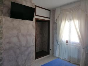 a bedroom with a television on the wall and a window at Sardinia B&B house in Olbia