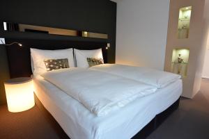 TägerwilenにあるJUCKERs Boutique-Hotelのランプ付きの客室内の大きな白いベッド