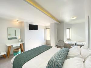 a bedroom with a bed and a television and a tub at Panorama Boutique Hotel in Fira