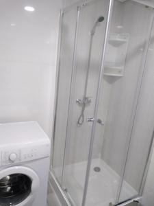 a shower with a glass door next to a washing machine at Apartamento Balsa 2 in Viseu