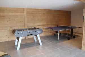 2 tafeltennistafels in een kamer met houten wanden bij Chalet de la Rigue in La Bresse
