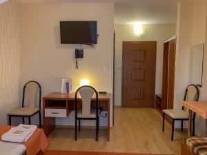 a room with a desk with two chairs and a television at Hotel Ostoja in Bobowa