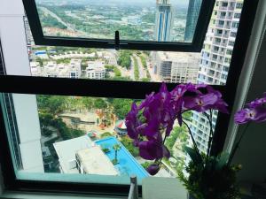 a vase of purple flowers sitting in a window at D'Gunduls Homestay STUDIO by DGH I-CITY in Shah Alam