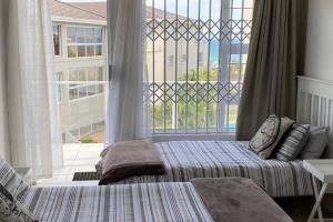 a bedroom with two beds and a large window at Uvongo Chalets 12 in Margate