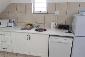 a kitchen with a sink and a white refrigerator at Uvongo Chalets 12 in Margate