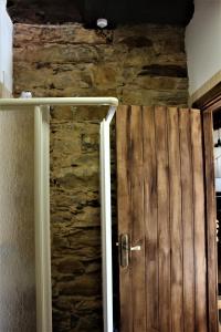 a wooden door in a room with a stone wall at Alojamientos Serra da Lastra in Villar de Silva