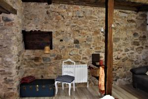 Habitación con pared de piedra, mesa y sillas. en Alojamientos Serra da Lastra, en Villar de Silva