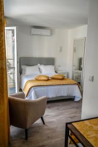 1 dormitorio con cama, silla y espejo en AQUACHAVES - Apart Studios, en Chaves