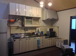 a kitchen with white cabinets and a refrigerator at Machiya Kyoto Shogoin in Kyoto