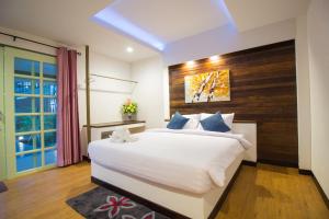 a bedroom with a large white bed with a wooden headboard at Annowa Resort - Chanthaburi in Chanthaburi