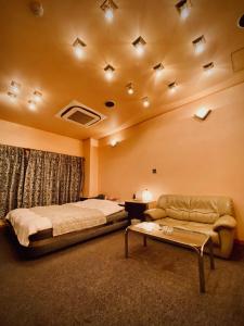 1 dormitorio con cama, sofá y mesa en Hotel Sagano (Adult only) en Kioto