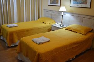 2 camas en una habitación de hotel con sábanas amarillas en Hotel Solar del Acuario, en Salto