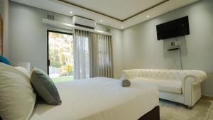 een slaapkamer met een wit bed en een tv aan de muur bij Cozy Forest B&B in Kingsborough