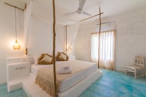 a white bedroom with a canopy bed and blue floors at Guru Canggu in Canggu