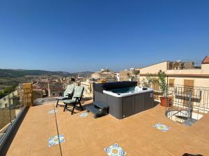 a balcony with a hot tub and a chair on a roof at Vista Baglio Grande in Sambuca di Sicilia