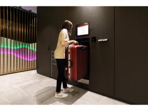 a woman is pulling a red suitcase in a elevator at Henn na Hotel Nara in Nara