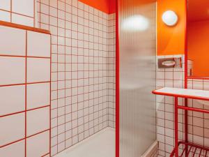 La salle de bains est pourvue d'une douche et de murs carrelés blancs. dans l'établissement Ibis Styles Madrid City Las Ventas, à Madrid