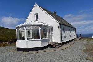 a white building with a window on the side of it at Waterfall View in Milovaig